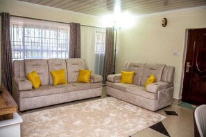 Relax in this inviting living room with two sofas, a large window, and a cozy rug.