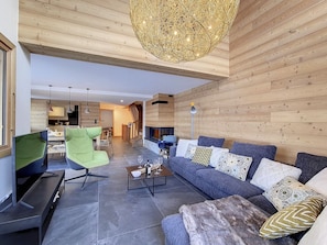 A modern living room with a fireplace, a green chair, a grey sofa, and a coffee table. - Luxury Chalet · Sauna · Fireplace · Garage · Near the Slopes (Saint-Martin-de-Belleville-Les Menuires)