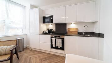 A modern kitchen with white cabinets, a microwave, a coffee maker, and a sink.