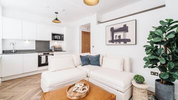 A modern living room with a white sectional sofa, a wooden coffee table, and a potted plant.