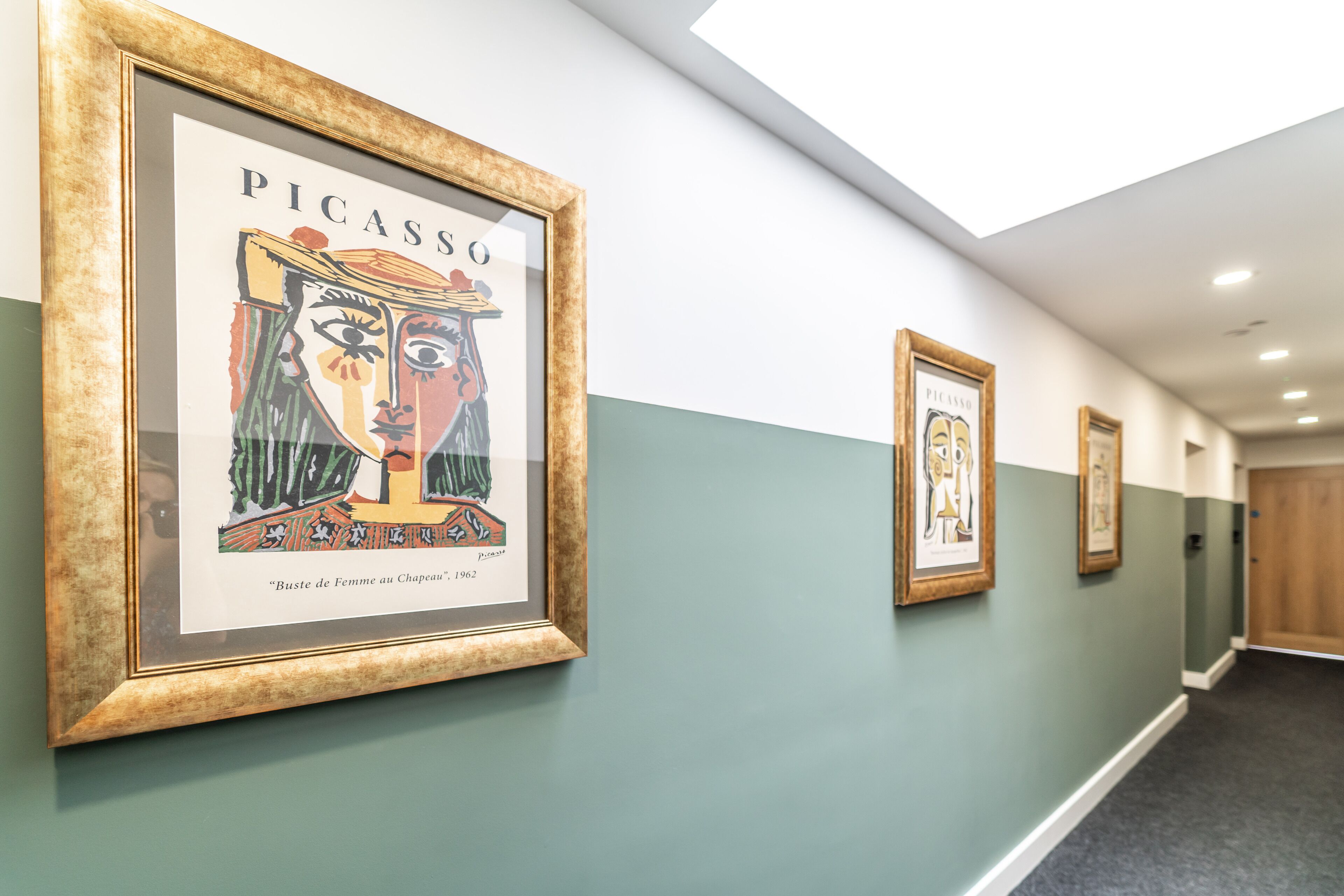 En gang med indrammede kunstværker på væggene, heriblandt et værkt af Picasso.