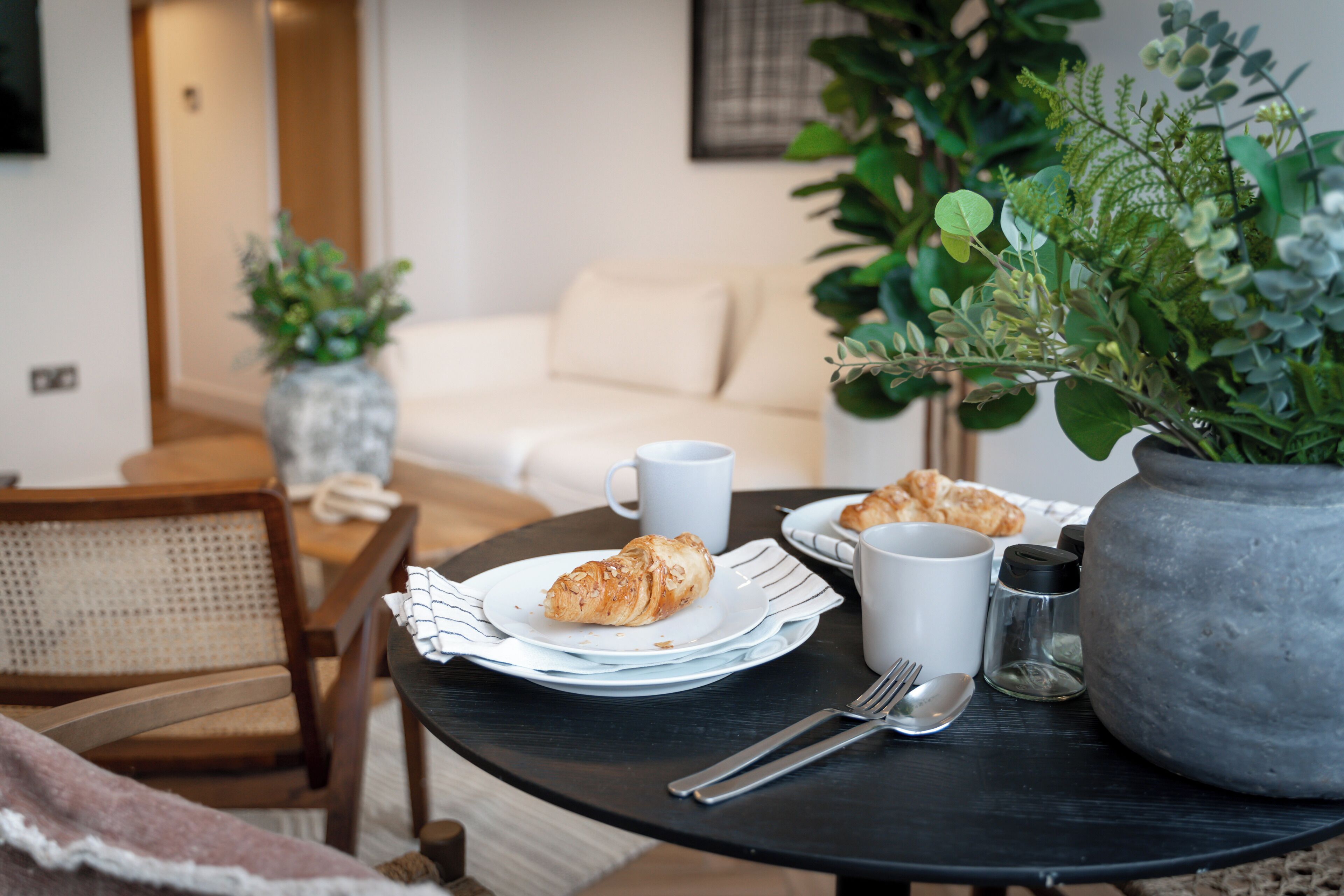 Une table à manger avec des croissants, une tasse et des salières et poivrières.