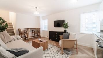 A modern living room with a sofa, coffee table, and a dining area with chairs.