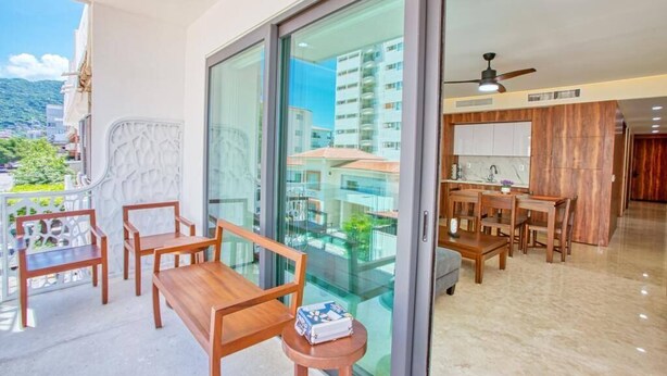 A balcony with wooden furniture and a view of a cityscape.