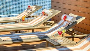 A poolside area with lounge chairs, towels, and drinks.