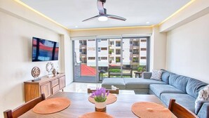 A modern living room with a dining table, sofa, and a ceiling fan.