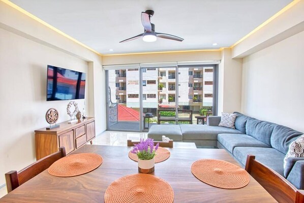 A modern living room with a dining table, sofa, and a ceiling fan.
