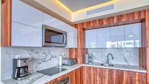 A modern kitchen with a microwave, coffee maker, and sink.