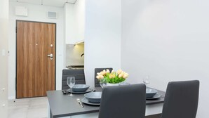 Un comedor moderno con una puerta de madera, una mesa puesta con platos, vasos y un florero con flores.