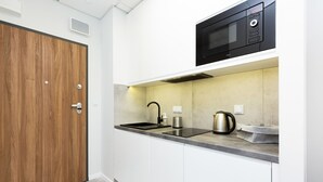 Una cocina moderna con puerta de madera, un microondas integrado, una tetera y una cafetera sobre la encimera.