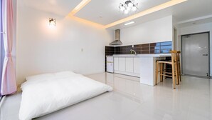 A modern, minimalist bedroom with a large bed, a small kitchenette, and a bathroom. - Namhae Spring, Summer, Fall, Winter Pet- (Namhae)
