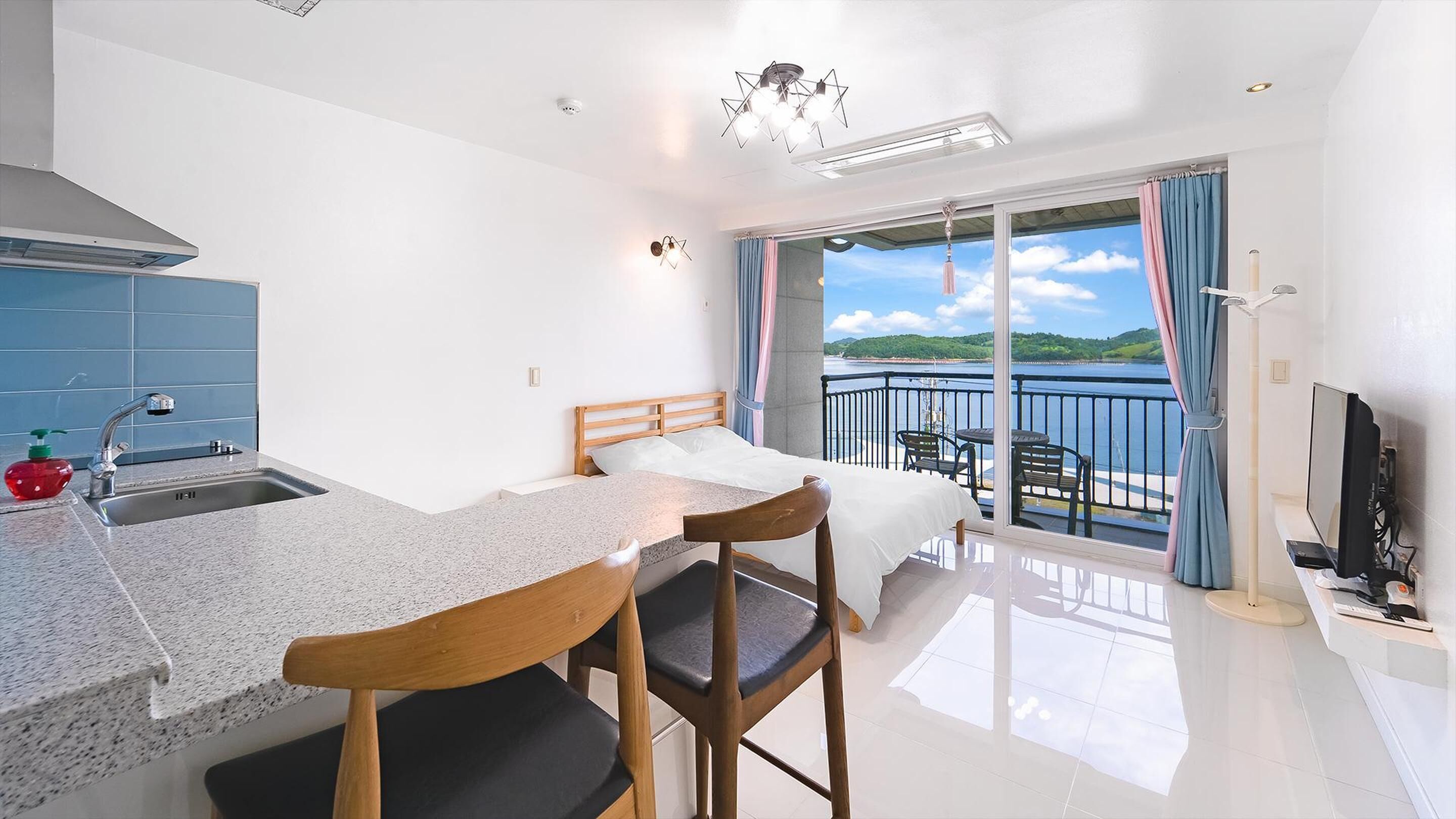 Een moderne slaapkamer met een bed, een bureau en een balkon met uitzicht op zee.