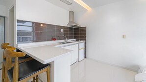 A modern kitchen with a white countertop, a stainless steel range hood, and a window with a view. - Namhae Spring, Summer, Fall, Winter Pet- (Namhae)