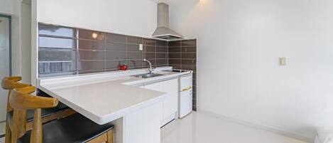 A modern kitchen with a white countertop, a stainless steel range hood, and a window with a view.