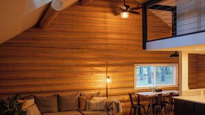 L’intérieur d’un chalet confortable, avec un plafond en bois, un canapé, une table à manger et un coin cuisine.