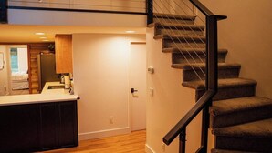 Une cuisine moderne avec des meubles de couleur sombre, un plan de travail blanc et un plancher en bois.