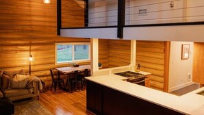 Une cuisine moderne dotée d’un îlot central, de planchers en bois et d’un coin repas avec une table et des chaises.