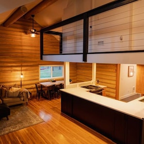 Een moderne keuken met een centraal eiland, houten vloeren en een eethoek met tafel en stoelen.
