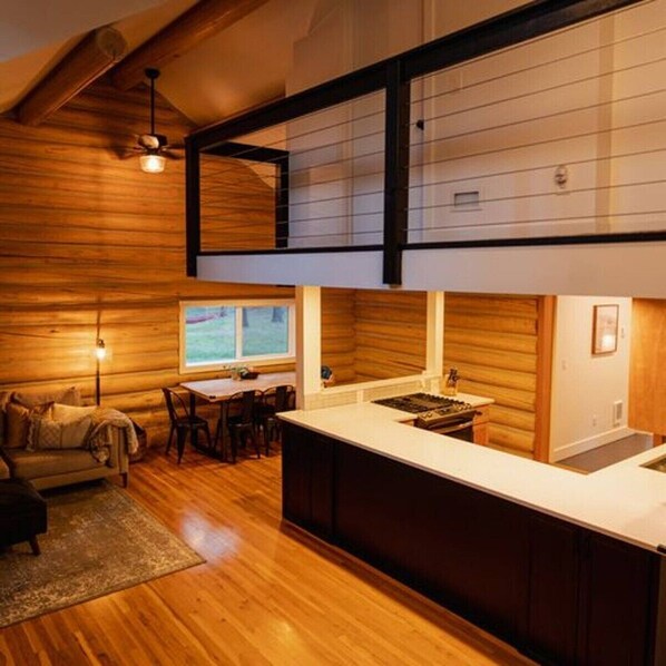 Une cuisine moderne dotée d’un îlot central, de planchers en bois et d’un coin repas avec une table et des chaises.