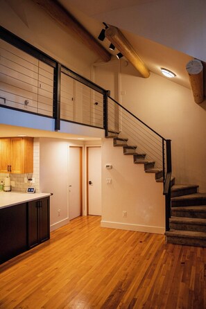 A spacious kitchen with wooden cabinets, a countertop, and a clock.