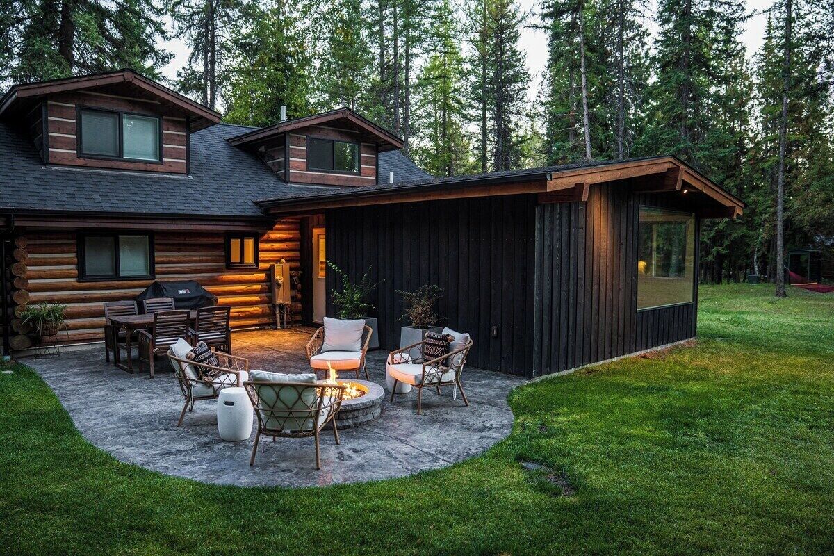 A log cabin with a patio area featuring outdoor furniture and a fire pit.