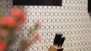Eine Küche mit modernem Design, ausgestattet mit einer Holzarbeitsplatte, einem schwarzen Herd und einer sechseckig gemusterten Spritzschutzeinrichtung.