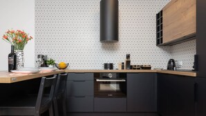 Eine moderne Küche mit Backofen von Bosch, schwarzen Schränken, einer Holz Arbeitsplatte und einer sechseckig gemusterten Spritzschutzleiste.