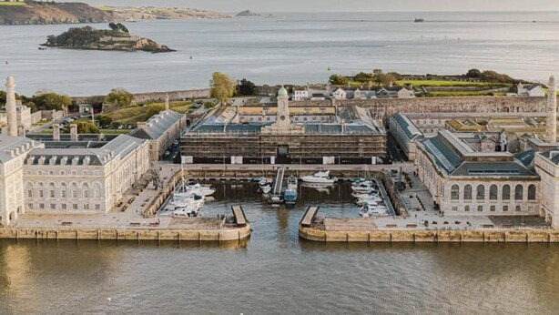 A coastal marina with multiple docks and boats, surrounded by historic buildings and a large body of water. - Cozy Coastal Apartment (Plymouth)