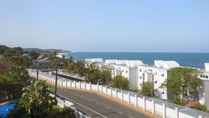 Ein Küstenhotel mit weißen Gebäuden, einer Straße und Blick aufs Meer.