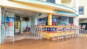 An outdoor bar area with a counter, multiple chairs, and a tropical mural.