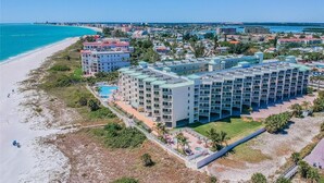 A coastal hotel with multiple buildings, a beach, and a clear view of the ocean.