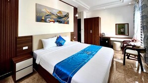 Ett hotellrum med en stor säng, ett skrivbord, en stol, en garderob och en tavla på väggen.