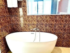 A freestanding bathtub in a bathroom with a patterned tile backsplash. - Ngoc Ha Hotel (Lao Cai)
