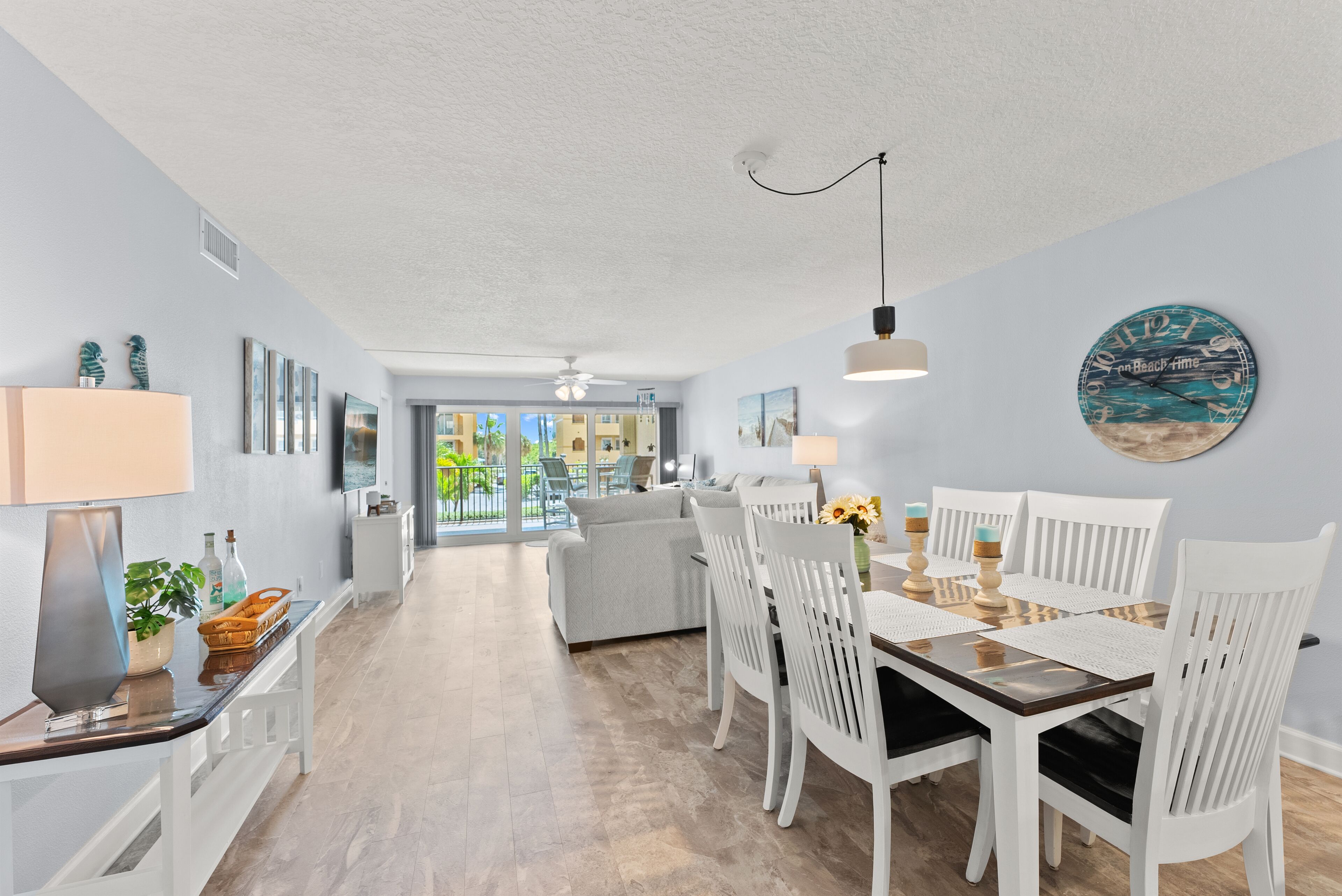 Un vaste espace de vie comprenant une table à manger, des chaises blanches et une vue sur l’extérieur.
