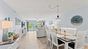 Un espacio habitable amplio con una mesa de comedor, sillas blancas y vistas al exterior.