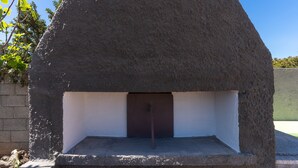 A stone oven with a metal door, surrounded by a concrete base and a brick wall. - 2842 Villa Colomba - Appartamento A by Barbarhouse (Nardò)