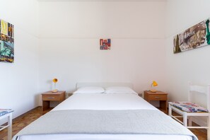 Ein Schlafzimmer mit einem großen Bett, zwei Nachttischen mit Lampen, einem Sessel und zwei Wandbildern.