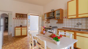 A kitchen with a dining table, chairs, a stove, and cabinets. - 2842 Villa Colomba - Appartamento A by Barbarhouse (Nardò)