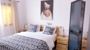 Un dormitorio con cama, dos mesitas de noche, un armario y un cuadro.