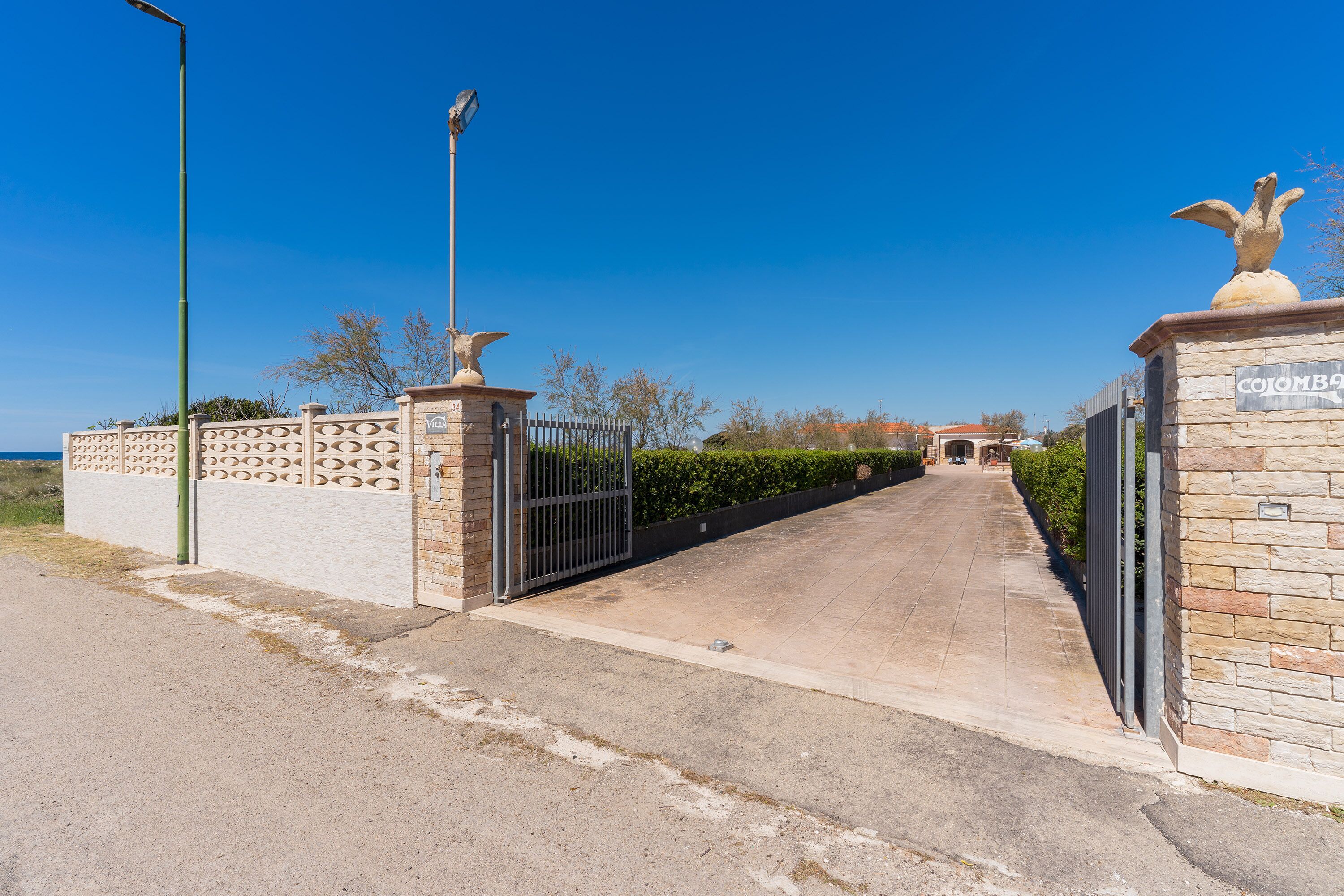 Une entrée fermée par un portail, avec un chemin dégagé menant à un bâtiment.