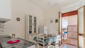 A kitchen with a gas stove, white cabinets, and a dining area with a table and chairs.