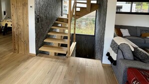 Ein modernes Interieur mit einer Holztreppe zu einem Erkerbereich, einem grauen Sofa und einem Holzboden.