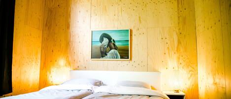 A wooden-paneled room with a bed, a nightstand, and a wall-mounted picture.