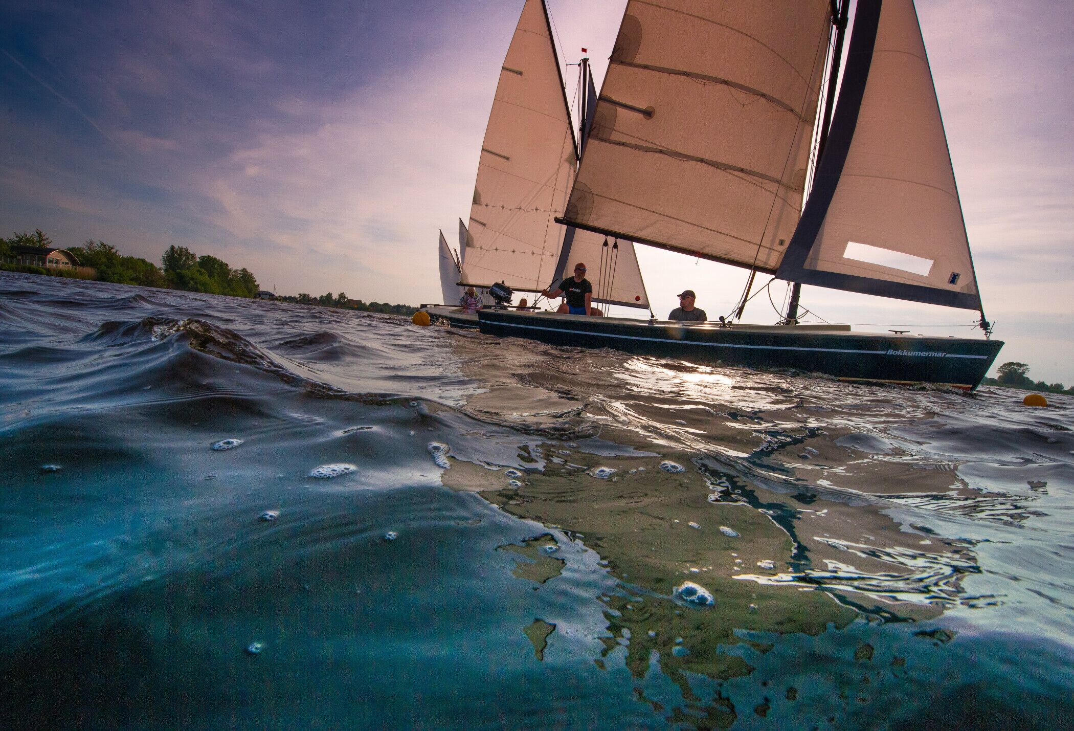 Ein Segelboot mit mehreren Segeln auf ruhigem Wasser.