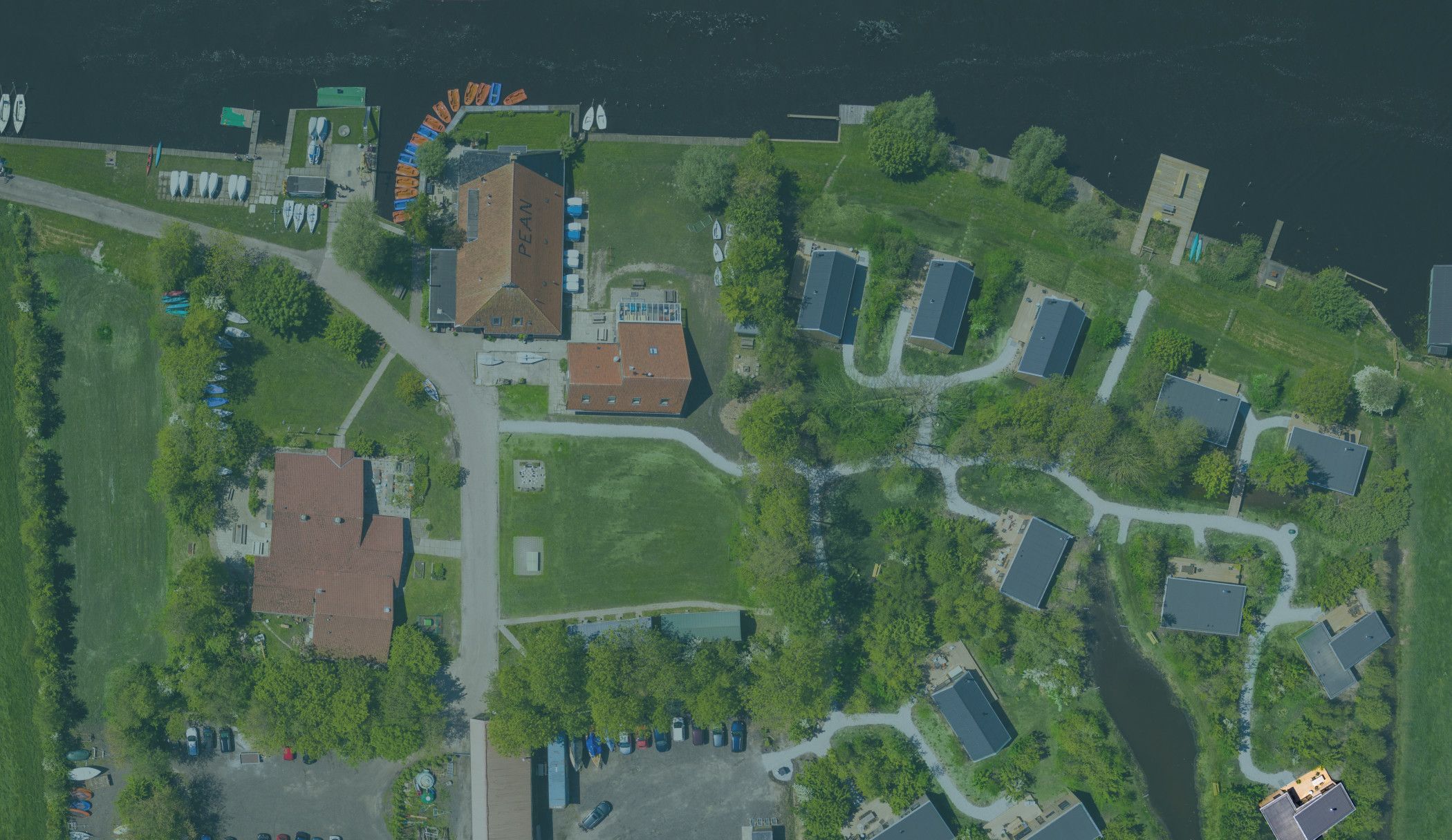 An aerial view of a lakeside property with multiple buildings, a parking area, and boats.