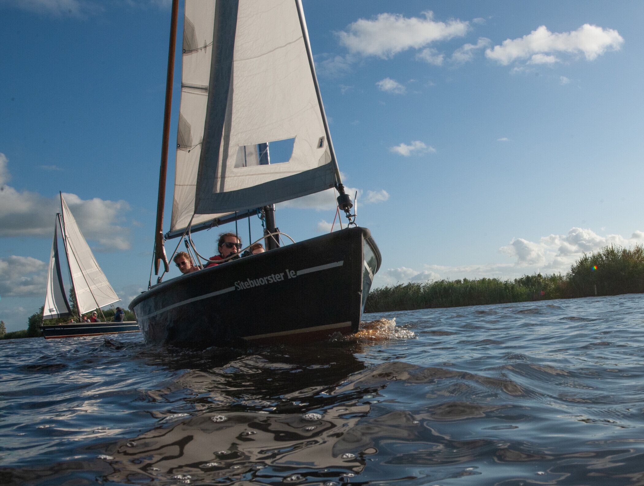 A sailboat with a name on the side, sailing on water.
