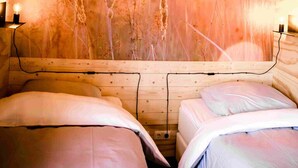 Ein Zimmer mit zwei Betten, einer großen Wandmalerei von hohem Gras und einer hängenden Leuchte.