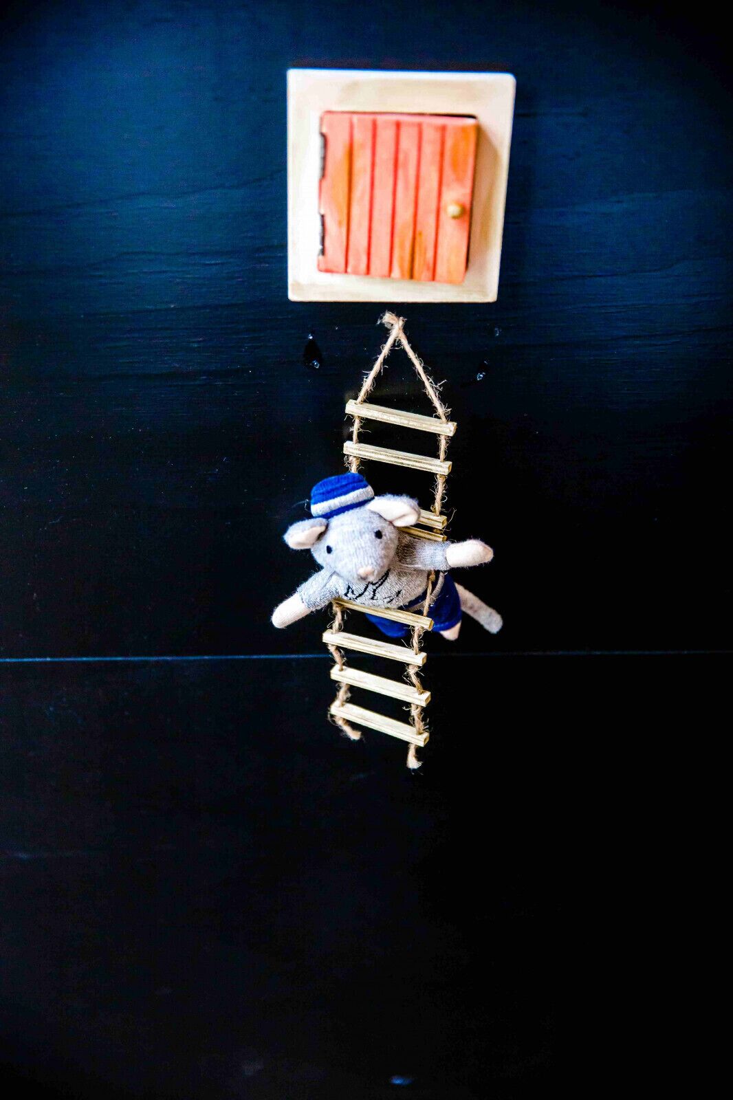 A small wooden ladder with a plush toy at the bottom, set against a dark background.