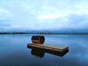 Eine Holzstege, der sich in einen ruhigen See erstreckt, mit einem Fass darauf.