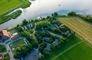 An aerial view of a lakeside residential area with houses, a dock, and boats. - Waterlodge Goudule in Nes (Nes)